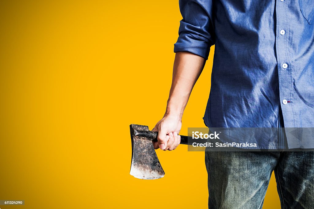 Man holding old rusty axe, on yellow background A guy holding old rusty axe, close up front view, on yellow background with copy space Axe Stock Photo