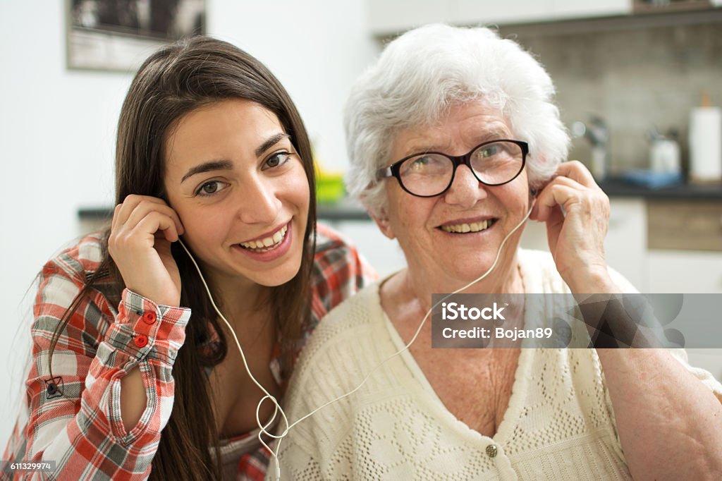 Granddaughter listening music with her grandmother at home. Listening Stock Photo