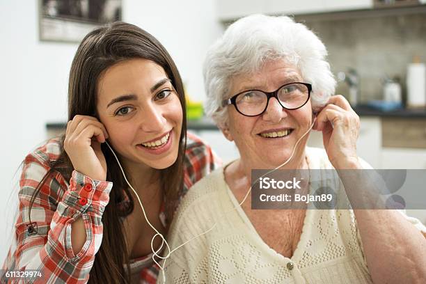 Granddaughter Listening Music With Her Grandmother At Home Stock Photo - Download Image Now