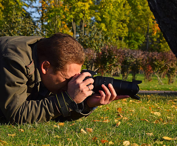 istock Photographer Photographing On Grassy Field 611457431