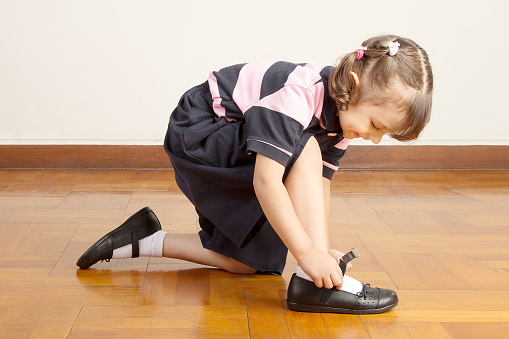 Little School Girl Tying her Black Shoes