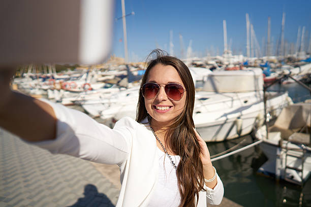 istock woman taking seflie in front of harbor 611602894
