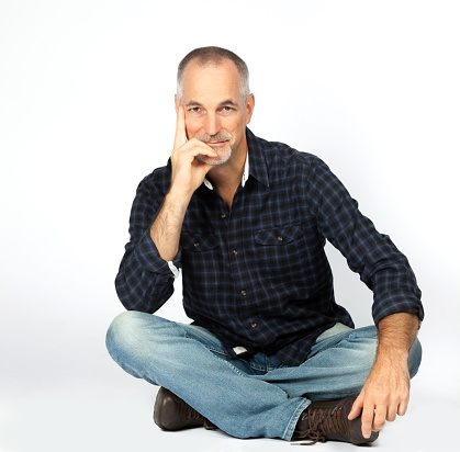 Handsome  mature hispanic man sitting informally on floor.