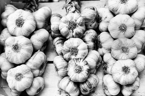 Black and white picture of garlic head braids in a market.