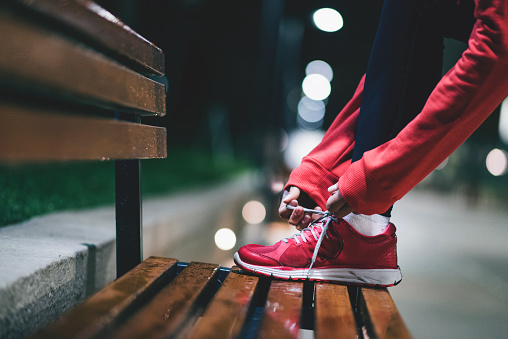 Young woman tying sneakers on park bench