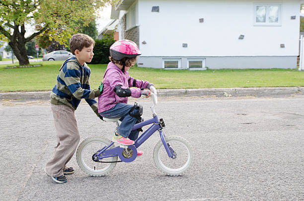 little boy helping his sister biking - helmet bicycle little girls child imagens e fotografias de stock