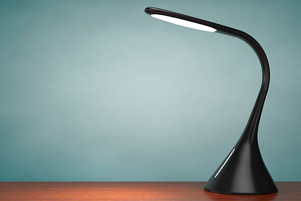 Desk lamp on table against yellow wall. This file is cleaned and retouched.