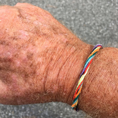 Friendship bracelet made of intertwined, multicolored strands of embroidery floss. Bracelet was made by a child for a grandparent.