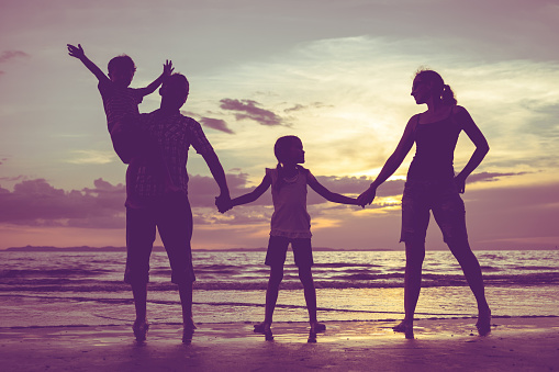 Silhouette of happy family who standing on the beach at the sunset time. Family having fun on the sea. Concept of friendly family and of summer vacation.Silhouette of happy family who playing on the beach at the sunset time. Concept of friendly family.
