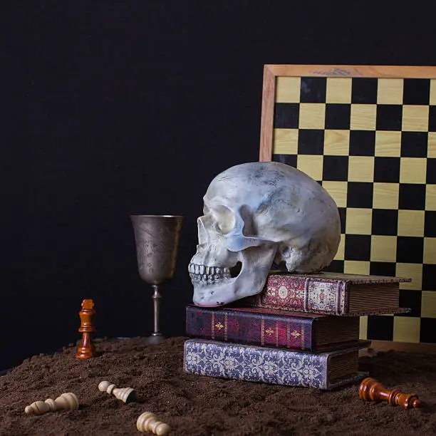 Halloween still life with skull, books and goblet of wine on a dark background