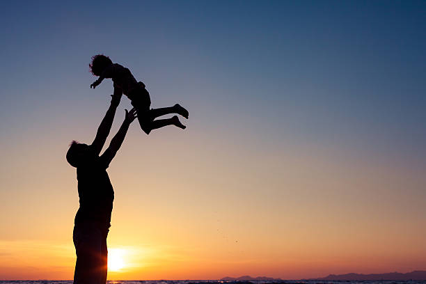 istock Father and son playing on the beach at the sunset. 611617502