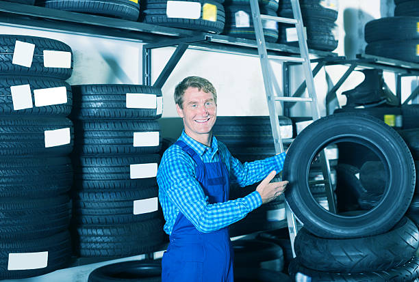 istock Glad mechanic man standing with new car tires 611617550