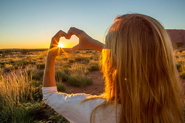 istock Woman frames sunset into heart shape finger frame 611619250