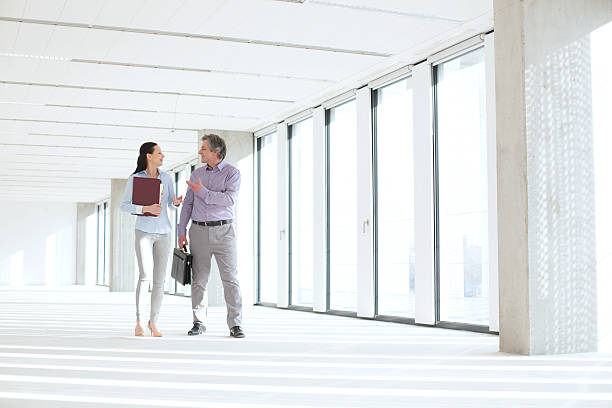 istock Businessman and businesswoman talking while walking in empty office 611619264