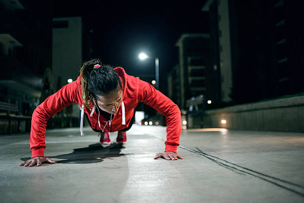 istock Young woman doing push-ups on pavement 611622782