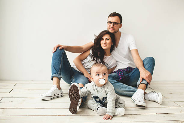 giovane hipster padre, madre e bambino sul pavimento in legno - floor two parent family couple home interior foto e immagini stock