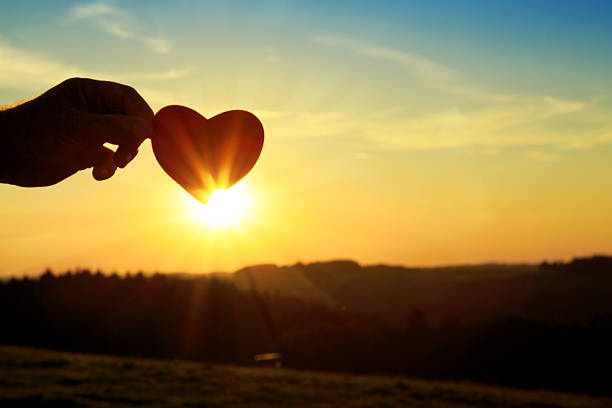istock Hand with paper heart at sunrise. 611625760