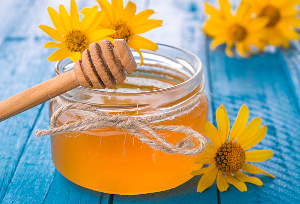 istock Honey in a glass jar with flowers 611627550
