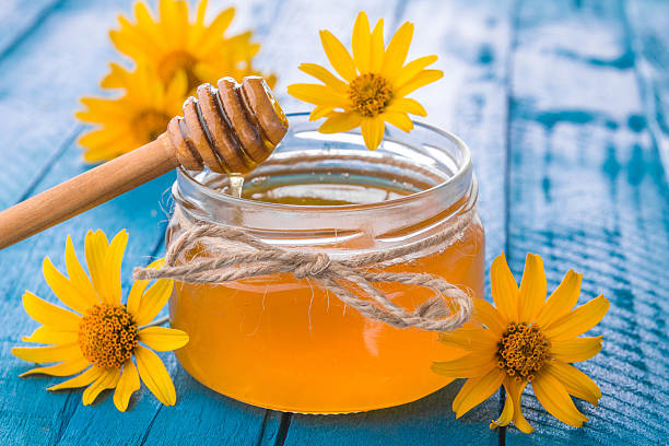 istock Honey in a glass jar with flowers 611627584