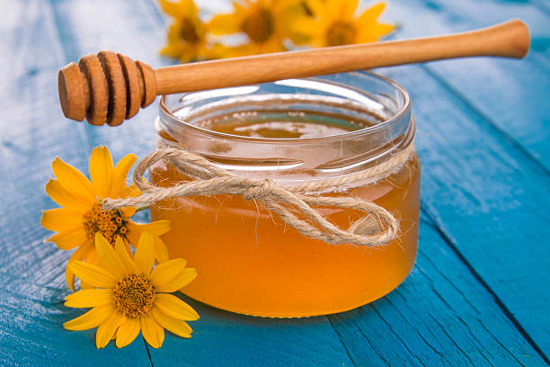 istock Honey in a glass jar with flowers 611627830