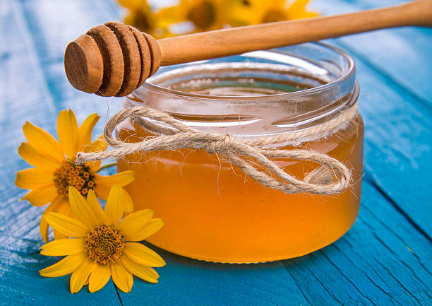 istock Honey in a glass jar with flowers 611627894