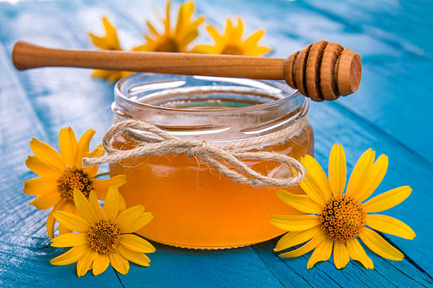 istock Honey in a glass jar with flowers 611627914