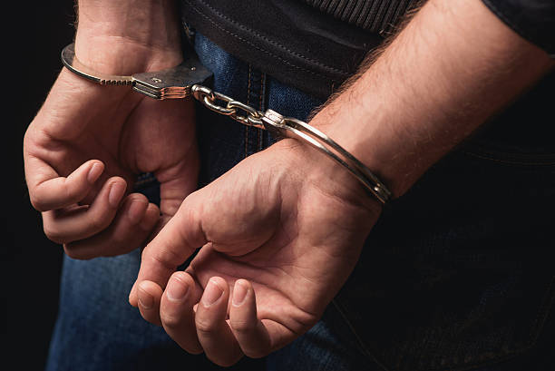 Young criminal standing in handcuffs Close up of male hands in bracelets behind back arrest photos stock pictures, royalty-free photos & images