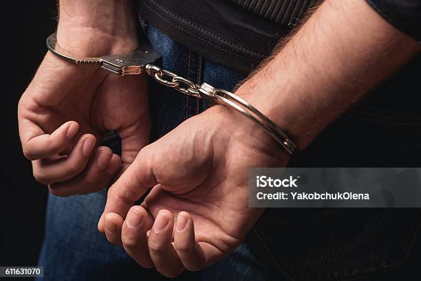 Young Criminal Standing In Handcuffs Stock Photo - Download Image Now - Arrest, Handcuffs, Criminal