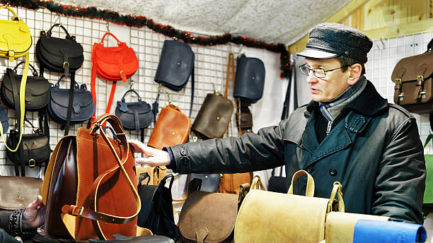 man offering handmade leather bags at vilnius christmas market - belt men gift night imagens e fotografias de stock