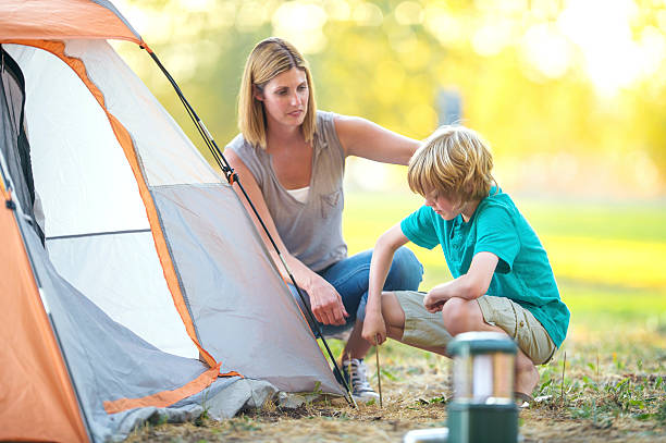 istock Mother helping son put tent stakes in the ground 611631498