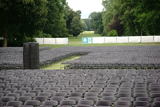 Seats outdoor concert Parallel arranged empty seat rows of folding chairs on a lawn of an open-air concert with an emergency exit. emergency exit photos stock pictures, royalty-free photos & images