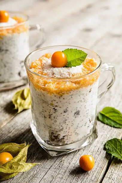 Probiotic yogurt with chia seeds, coconut, honey and physalis puree in a glass jar