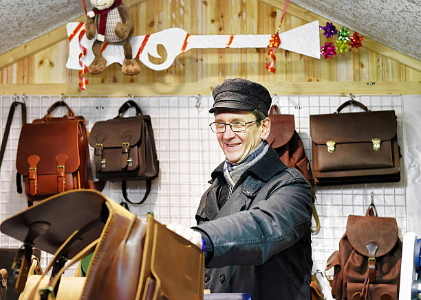 smilling man offering handmade leather bags at vilnius christmas market - belt men gift night imagens e fotografias de stock