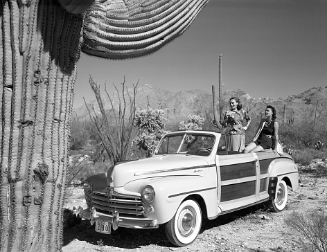 Tucson, Arizona, USA - November 4, 1947: Two young women enjoying a day in the Sonoran Desert near Tucson, Arizona from the back of a 1947 Ford Super DeLuxe Sportsman “woodie” convertible. Scanned film.
