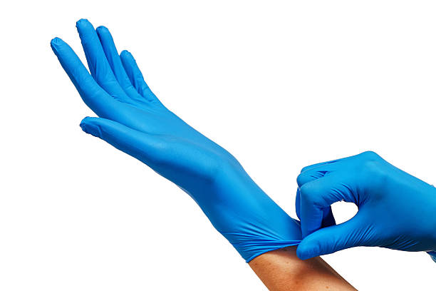 médico que se pone guantes azules protectores aislados sobre blanco - surgical glove fotografías e imágenes de stock