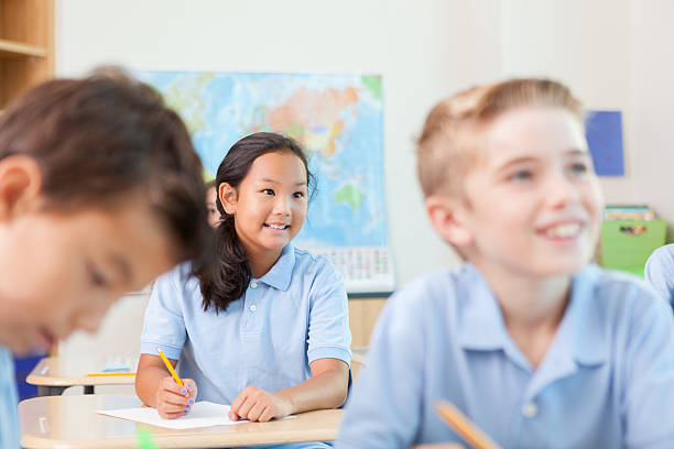 istock Young Asian elementary student listens to teacher in classroom 611634958