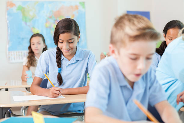 istock Pretty Hispanic schoolgirl works on homework in classroom 611634968