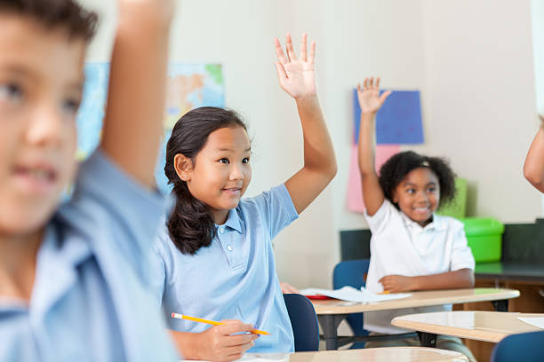 istock Cute schoolgirls raise their hands to answer question in class 611634974