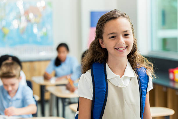 istock Elementary age schoolgirl with toothy smile in classroom 611635020