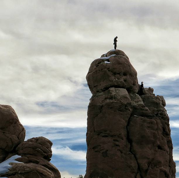 istock Arches National Park People Climbing Rock Formation Tower Snow 611635130
