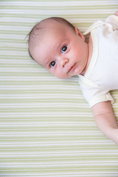 istock Baby Boy Laying on Green Striped Crib Sheet 611746694