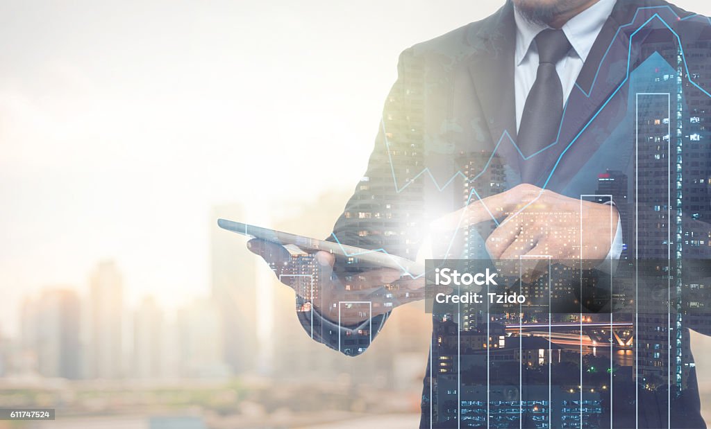 Double exposure of businessman using the tablet with cityscape Double exposure of businessman using the tablet with cityscape and financial graph on blurred building background, Business Trading concept Business Stock Photo