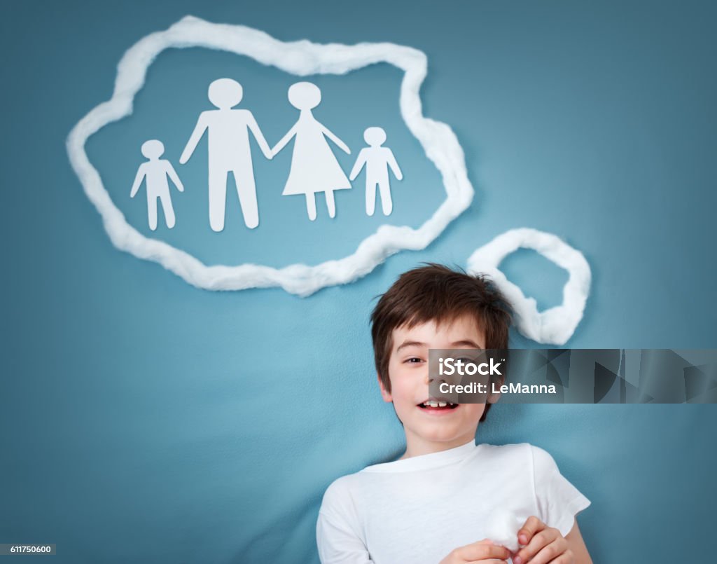 boy dreaming of a family seven years old boy dreaming of a family on blue background Adoption Stock Photo
