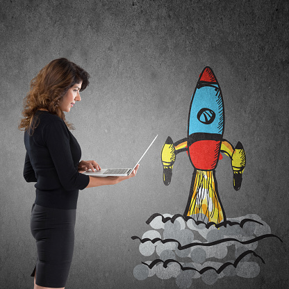 Businesswoman with laptop and rocket ship launch