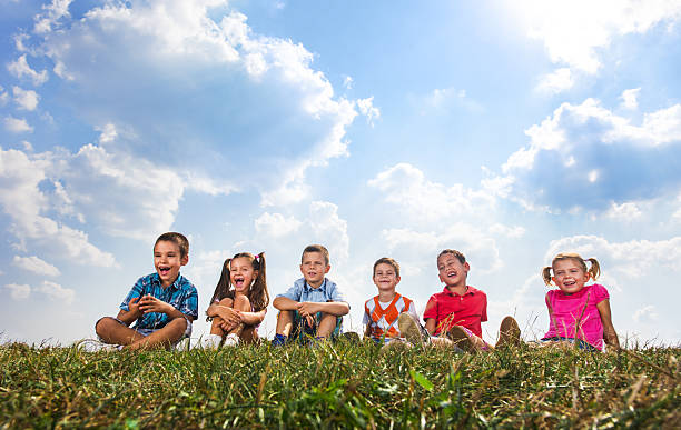 istock Group of cute kids relaxing together in grass. 611753606