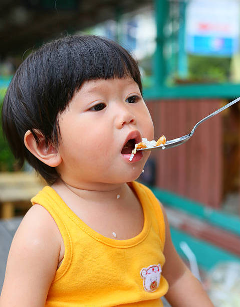 istock Little Asian baby eating rice by stainless spoon 611753826