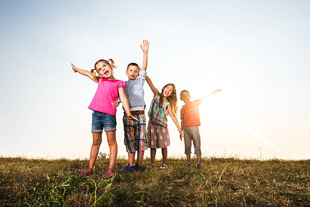 Group of cute children having fun with their arms outstretched in nature. Copy space.