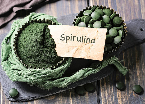 comprimés de spiruline dans un bol - chlorella spirulina bacterium algae nutritional supplement photos et images de collection