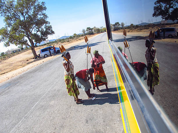 Bulawayo, Zimbabwe – August 20, 2016: women selling roasted corn on the cob to bus passengers on the road between Masvingo and Bulawayo. Roads in impoverished Zimbabwe are littered with petty sellers trying to earn some cash to support their families.
