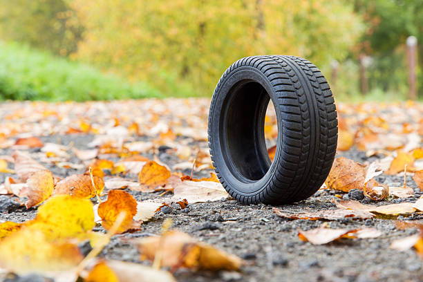 istock Black tire on the ground with fallen leaves in autumn. 611759330